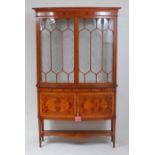 A circa 1900 satinwood and inlaid bowfront display cabinet by Maple & Co, in two sections, the upper