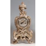 A Rococo Revival silvered bronze mantel clock, the swept case surmounted with a pedestal urn, the