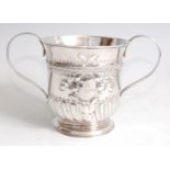 A George III silver twin handled loving cup, having floral repousee decoration and cartouche