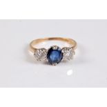 An 18ct sapphire and diamond ring, the central oval sapphire, approx. 6.5mm long, set to either side
