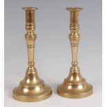 A pair of French 18th century turned brass candlesticks, having turn-off bases, 25cm