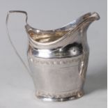 A late Georgian silver cream jug, of helmet shape, having reeded handle, bright cut decoration and