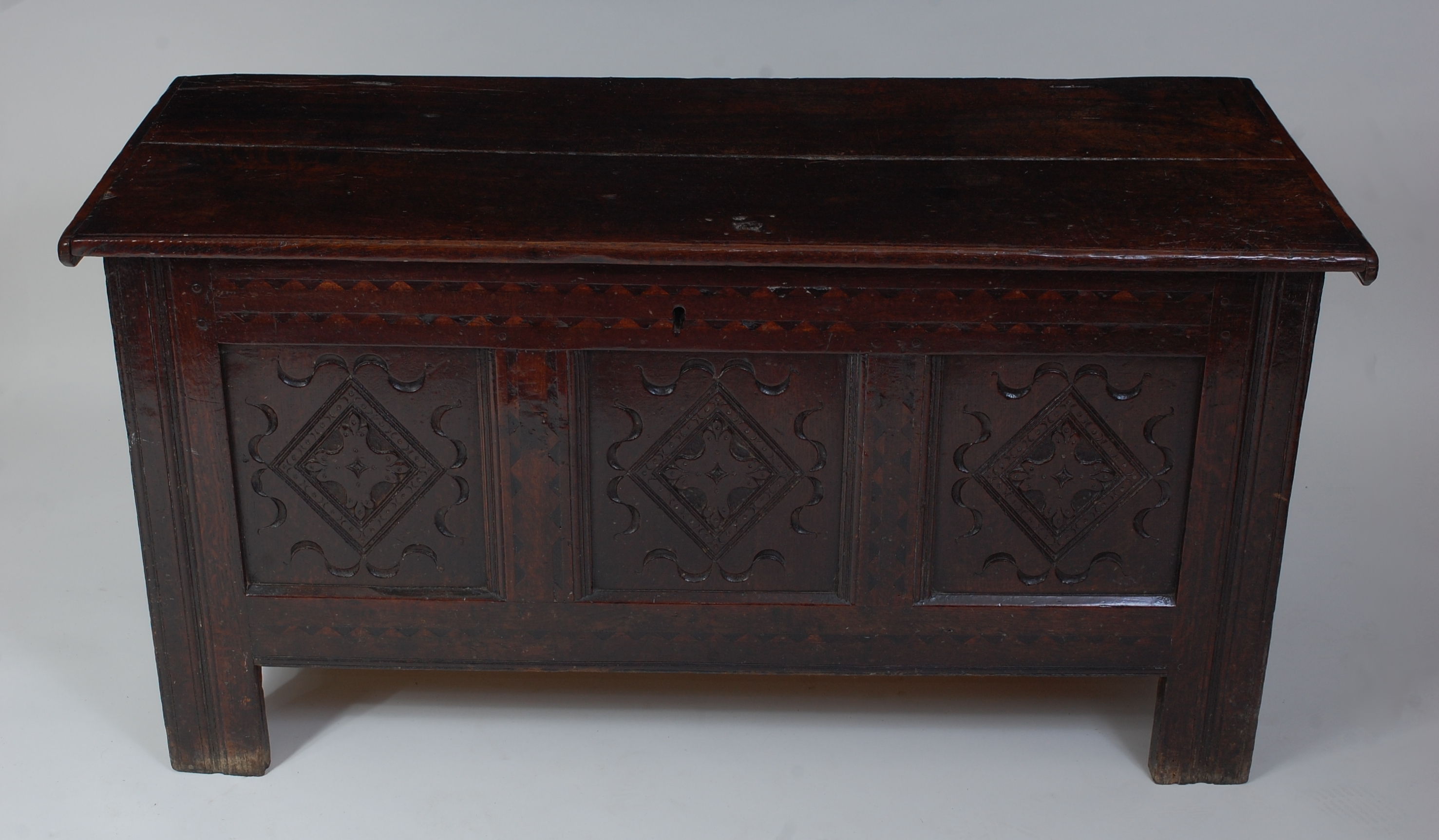 *An 18th century joined oak coffer, the two-plank top on split ring hinges, above a carved three