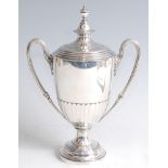 *A late Victorian silver pedestal twin handled cup and cover, the cover with urn finial, the body of