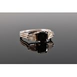 A platinum black and white diamond ring, the central modified cushion cut black diamond, estimated