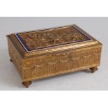 A late 19th century brass music box, the hinged cover cast with a scene of merry-making and