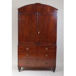 A late Regency mahogany linenpress, having an arched cornice above panelled doors enclosing four