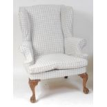 A walnut framed wing armchair, in the early 18th century style, the whole upholstered in a cotton