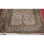 A Kashmiri hand-knotted silk rug, the cream ground decorated with a vase issuing scroll flowers