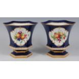 *A pair of Royal Worcester porcelain vases, each of waisted hexagonal form, the central reserve