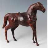 An early 20th century tan leather clad model of a standing bay horse, with glass inset eyes, in