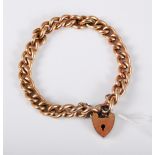 A gold plated curblink bracelet with heart shaped padlock clasp and safety chain, approx. 18cm long