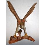 A large carved and painted model of an eagle, with outstretched wings and perched on a tree bough,