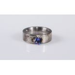 A silver and tanzanite ring, the round tanzanite, approx. 5mm diameter, claw mounted to a plain
