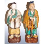 A Chinese terracotta figure of a sage in standing pose, glazed in shades of green, brown and yellow,
