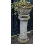 A pair of reconstituted stone circular garden planters, each raised on fluted pedestal columns, h.