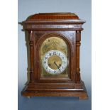 A late 19th century continental oak cased mantel clock, having engraved arched brass dial with