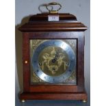 A modern mahogany cased mantel clock, the silvered dial with Roman numerals, within pierced brass