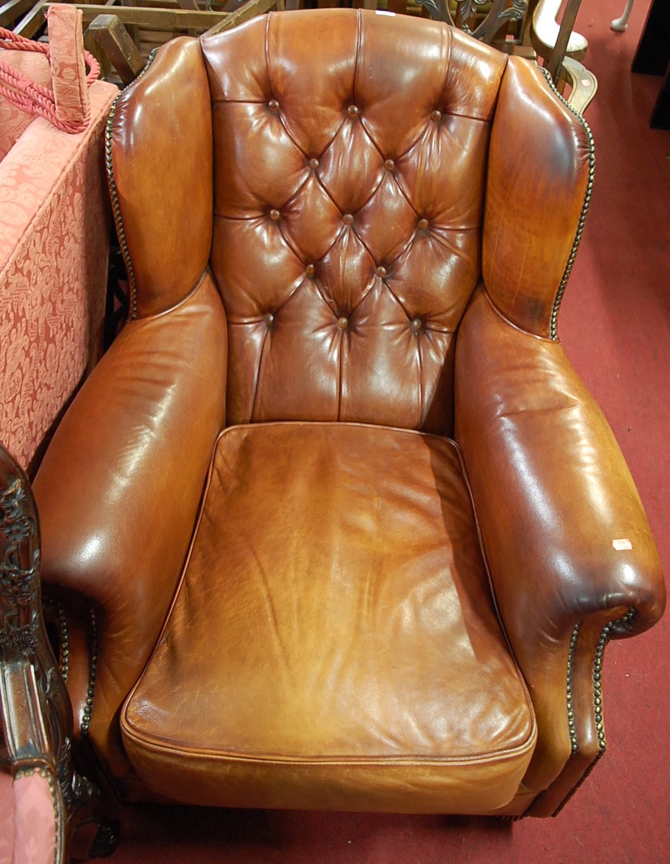 A good contemporary tan leather buttonback and brass studded wingback scroll club armchair, raised