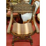 A Spanish heavily carved walnut X-framed open armchair, with acorn finials and grotesque mask