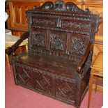 A 19th century heavily relief carved joined oak three panelled settle, having all-over profusely