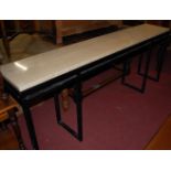 A contemporary polished travertine topped and black painted tubular metal based long hall table, w.