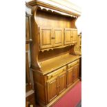 A modern stained pine dresser, having four upper panelled cupboard doors over base fitted with