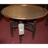 An Eastern engraved copper circular topped Benares table, raised on turned folding base, dia. 57.
