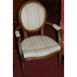 A pair of French walnut open fauteuil, each with floral carved detail and striped upholstery;