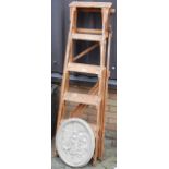 A pine easel decorator's ladder, together with a reconstituted stone Continental oval plaque