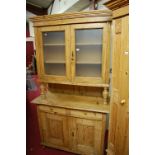 A provincial French pine kitchen dresser, having twin frosted glazed upper doors, the base with twin