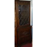 A contemporary moulded oak freestanding corner cupboard, having lead glazed upper door