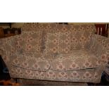 A pair of contemporary floral upholstered three-seater sofas, raised on turned forelegs (vendor