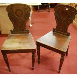 A pair of Regency mahogany panelled seat hall chairs raised on turned forelegs