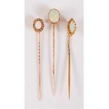 Three opal stick pins: to include a marquise opal cabochon and diamond highlight cluster stick