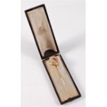 A painted ivory stick pin: the oval ivory panel painted with white, pink and red roses and purple