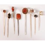 Eight gemset stick pins: a rock crystal with inset ruby and diamond highlight star (one diamond