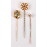 Three stick pins: to include an oval emerald and rose cut diamond stick pin, 14mm diameter; a