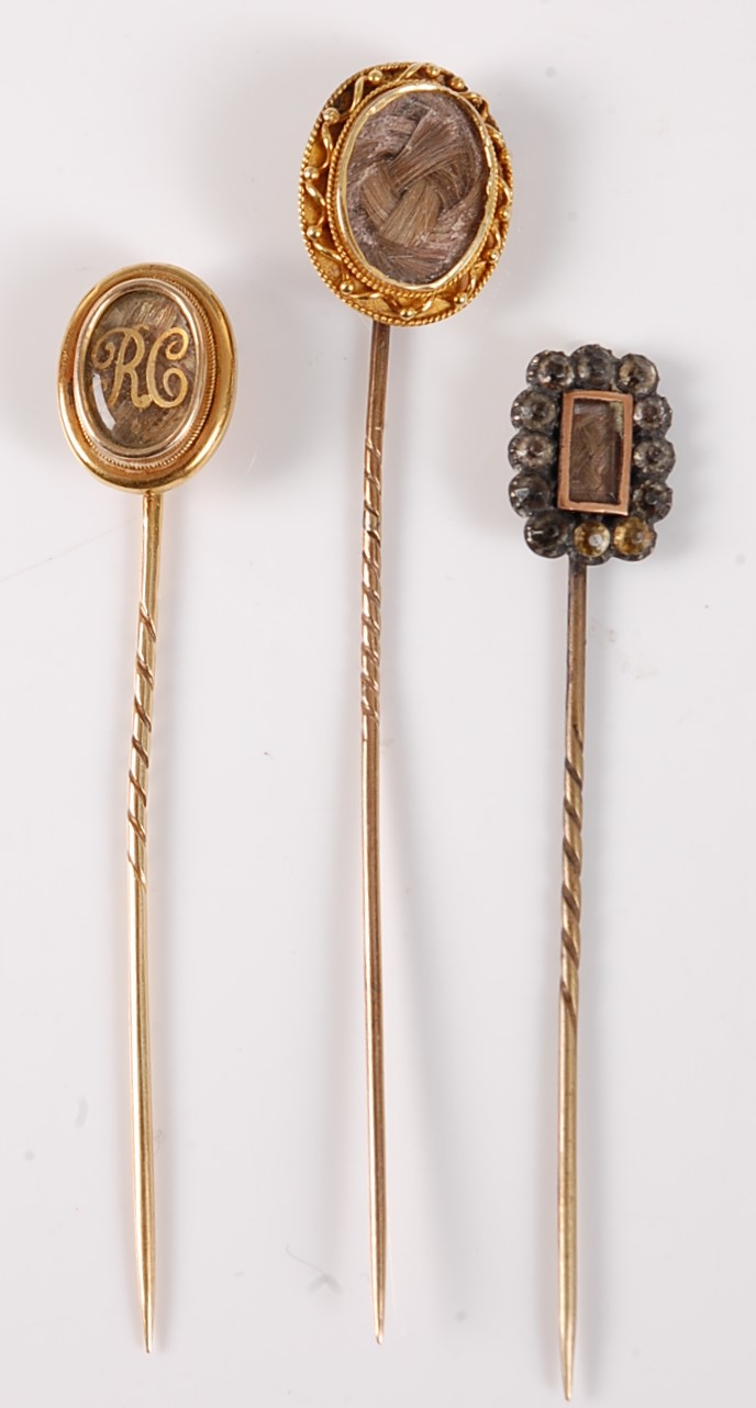 Three hairwork stick pins: an oval plaited hairwork stick pin, with glazed panel with painted