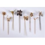 Eight various stick pins: a 9ct cat stick pin, 17mm wide, (5.5g); a 9ct miners stick pin, 17mm wide,