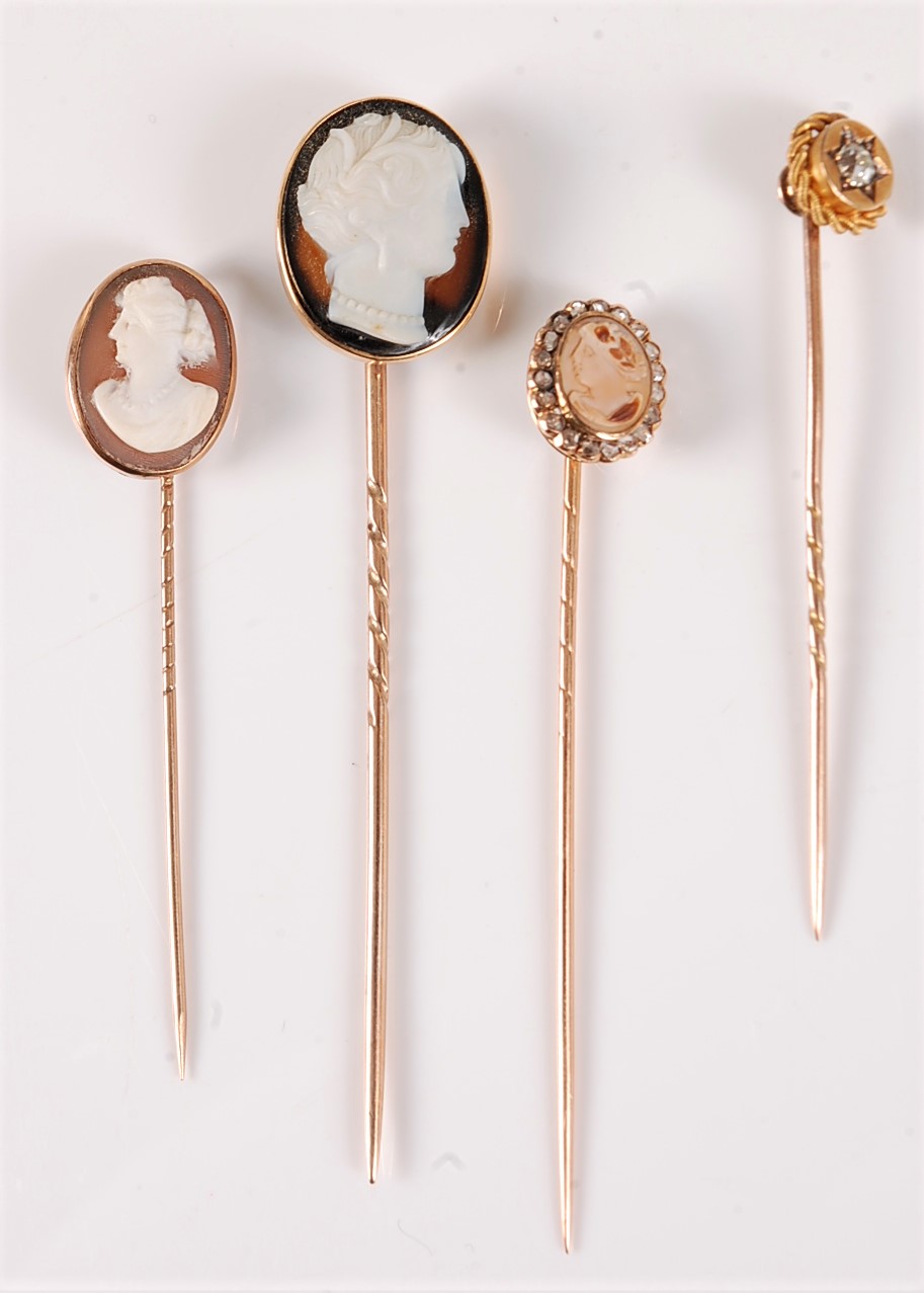 Three cameo stick pins and a diamond stick pin: a carved hardstone oval cameo of a classical lady,