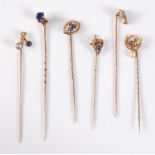 Six sapphire and seed pearl stick pins: a 15ct sapphire set eye stick pin, 10mm wide; a 15ct seed