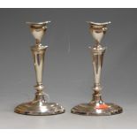 A pair of George V silver table candlesticks each having a removable sconce to tapering oval stem