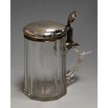An early 20th century German bierstein having faceted clear glass body with white metal mount with