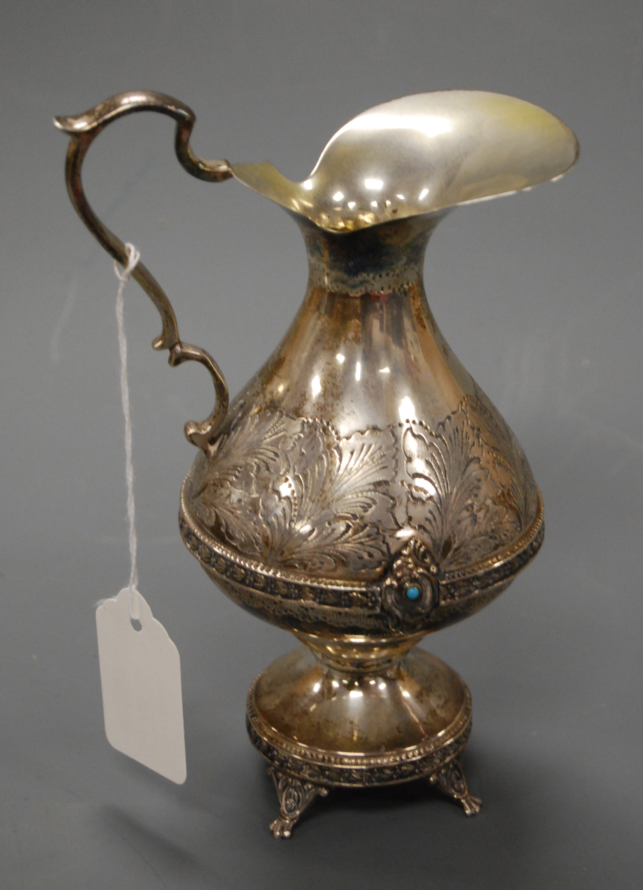 An early 20th century continental (Portugese?) white metal ewer having leaf etched decoration with a