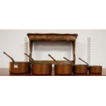 A graduated set of five copper saucepans; together with a beech saucepan rack