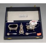 A modern silver three piece cruet set to include open salt with blue glass liner, mustard and