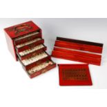 A mid-20th century Chinese mah-jong set, housed in a red lacquered gilt decorated fitted five drawer