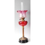 A late Victorian brass and cranberry glass pedestal oil lamp, with acid etched cranberry tinted
