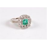 An early 20th century emerald and diamond ring, the central square emerald cut emerald, in rubover